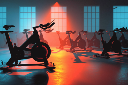 An empty gym studio before dawn with a reservation card knocked to the floor beside one bike