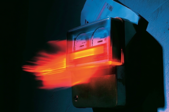 A domestic electricity meter spinning fast with a bill tucked behind it, representing a metered service billing incorrectly