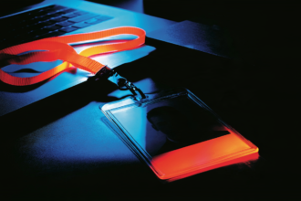 School ID badge on a desk beside a laptop, representing the verification requirement